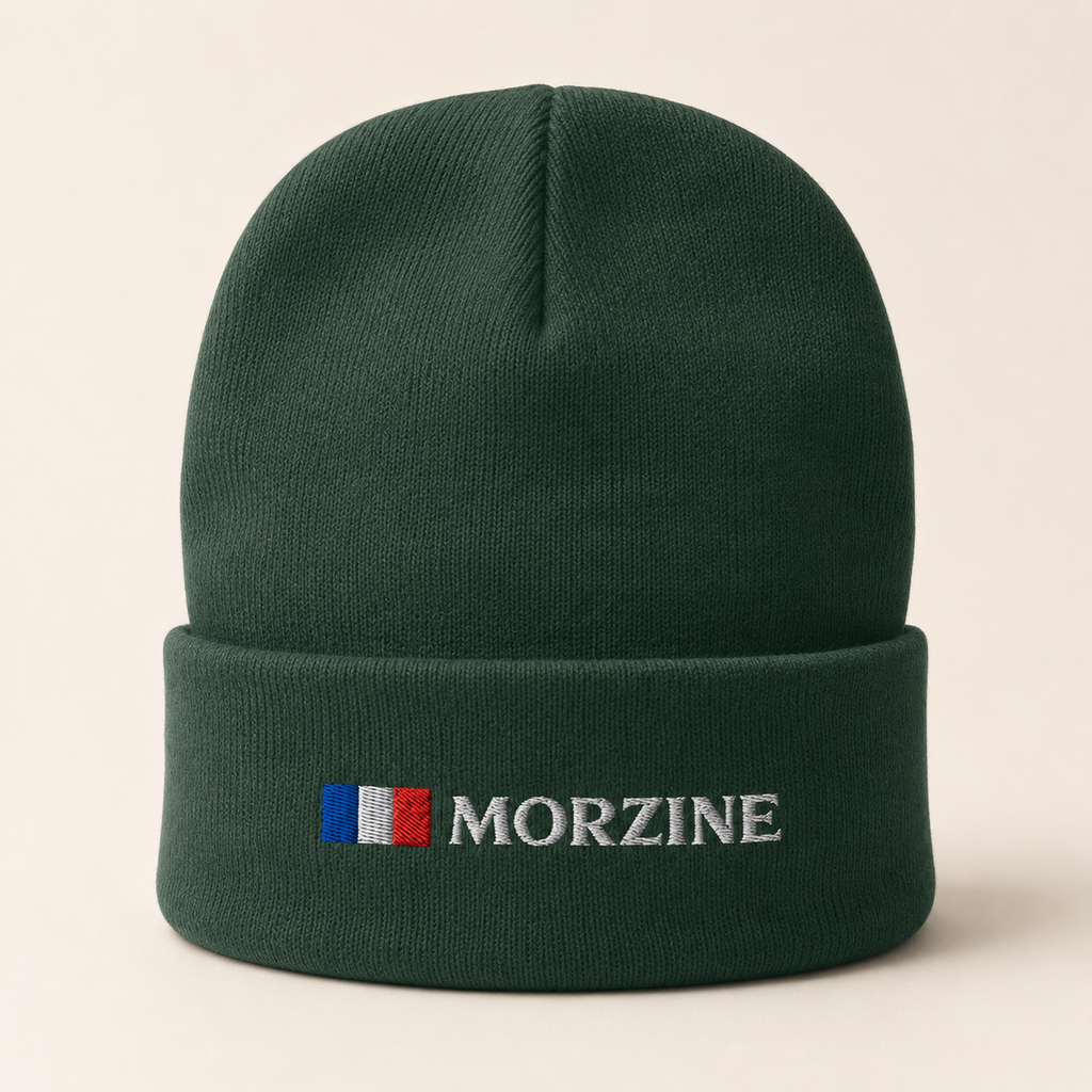 A dark green knit beanie hat with a folded cuff, featuring an embroidered French flag and the brand name 'MORZINE' in white on the front, set against a light beige background.