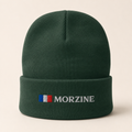 A dark green knit beanie hat with a folded cuff, featuring an embroidered French flag and the brand name 'MORZINE' in white on the front, set against a light beige background.