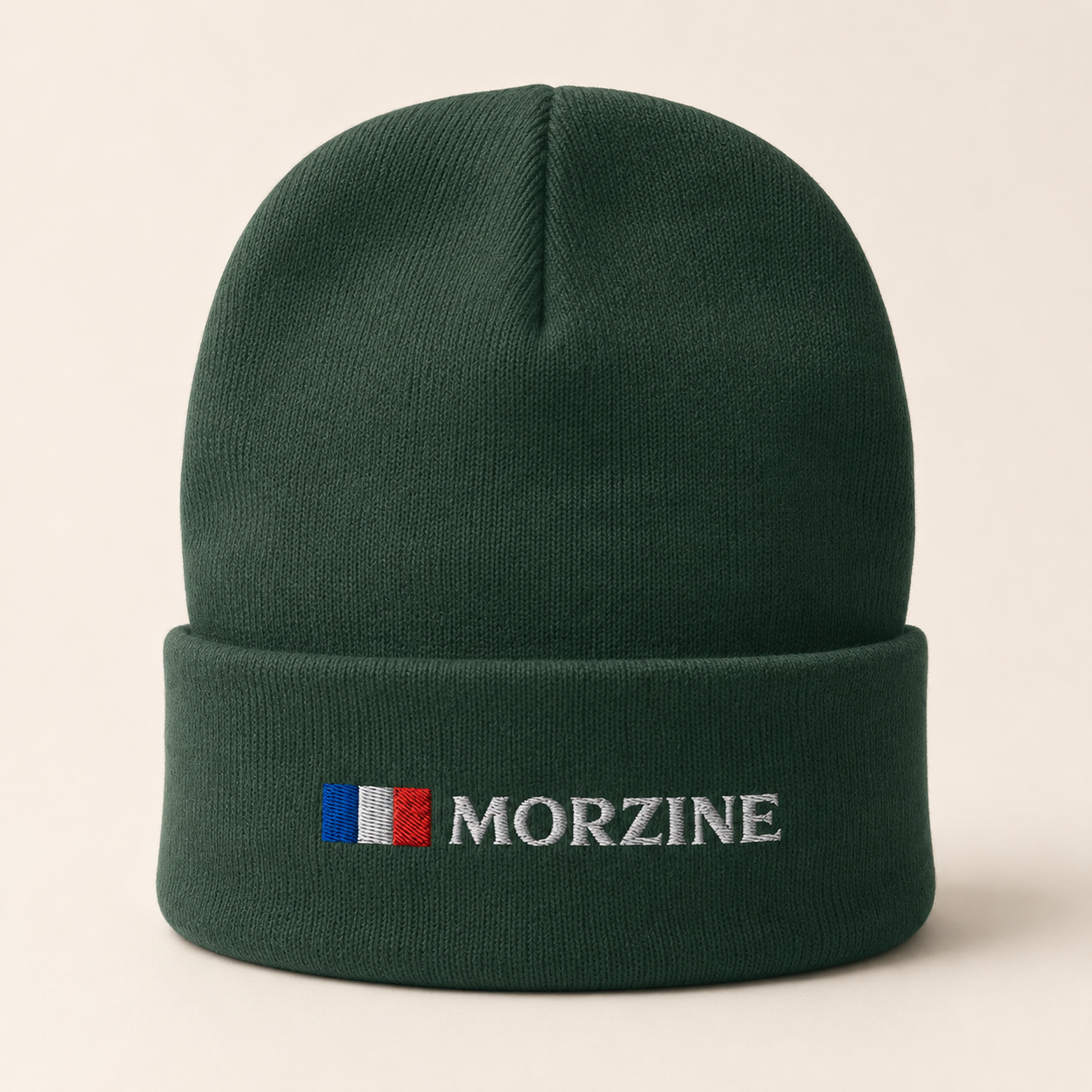A dark green knit beanie hat with a folded cuff, featuring an embroidered French flag and the brand name 'MORZINE' in white on the front, set against a light beige background.