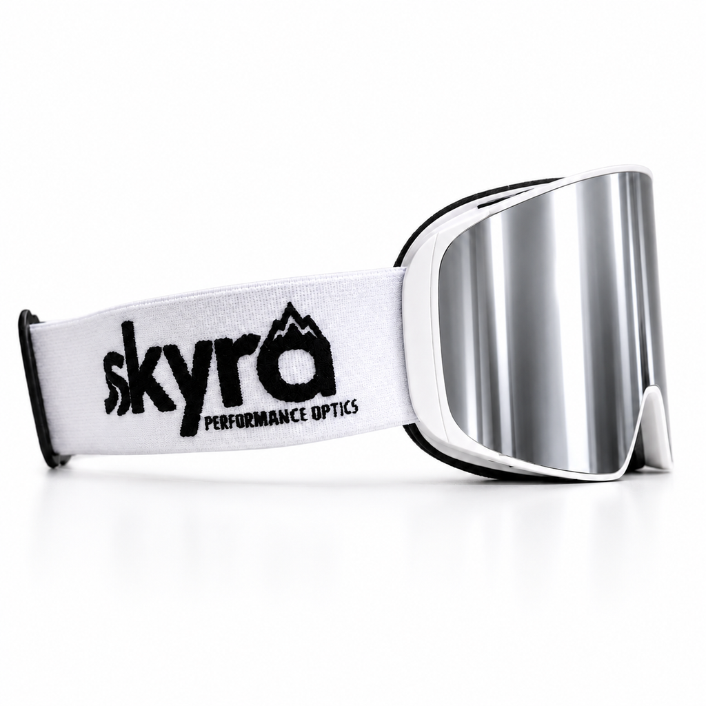 White ski snowboard goggles with silver mirror reflective lens featuring 'skyra Performance Optics' branding on a white strap.